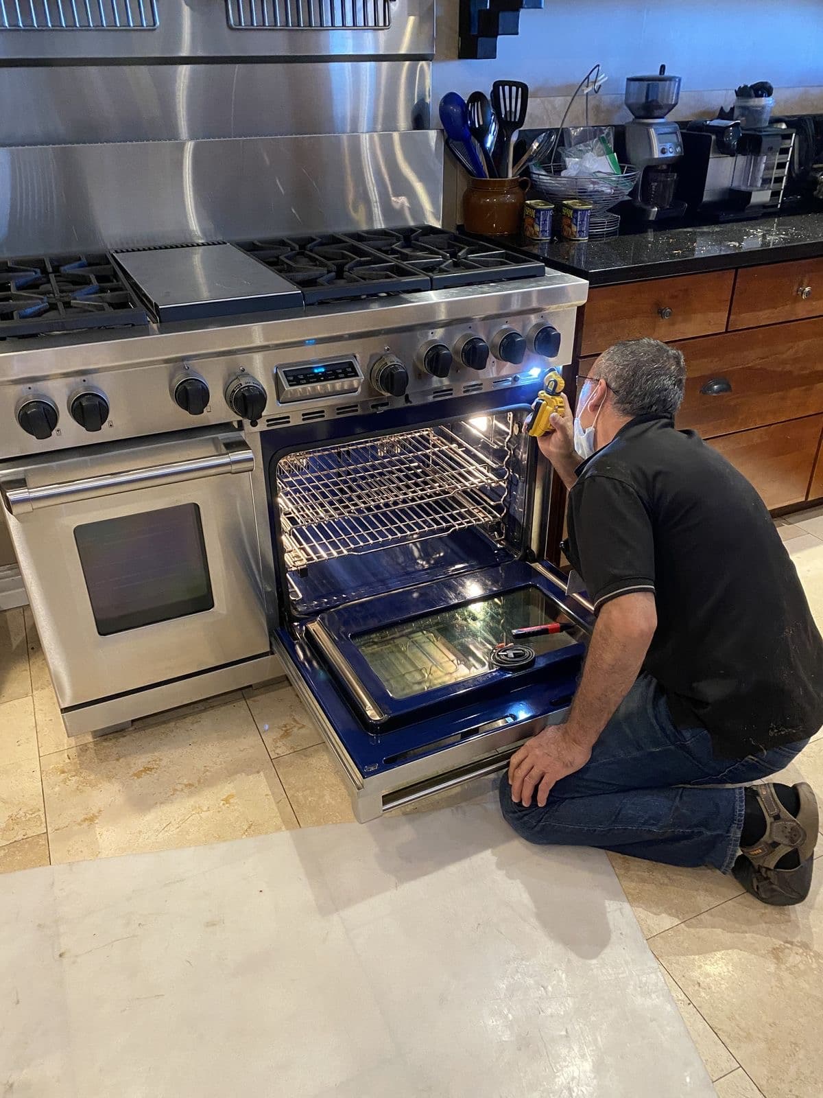 Technician using a diagnostic tool to inspect an open range oven