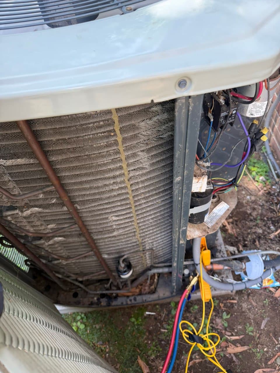 A dusty, dirt-caked outdoor AC condenser coil before cleaning
